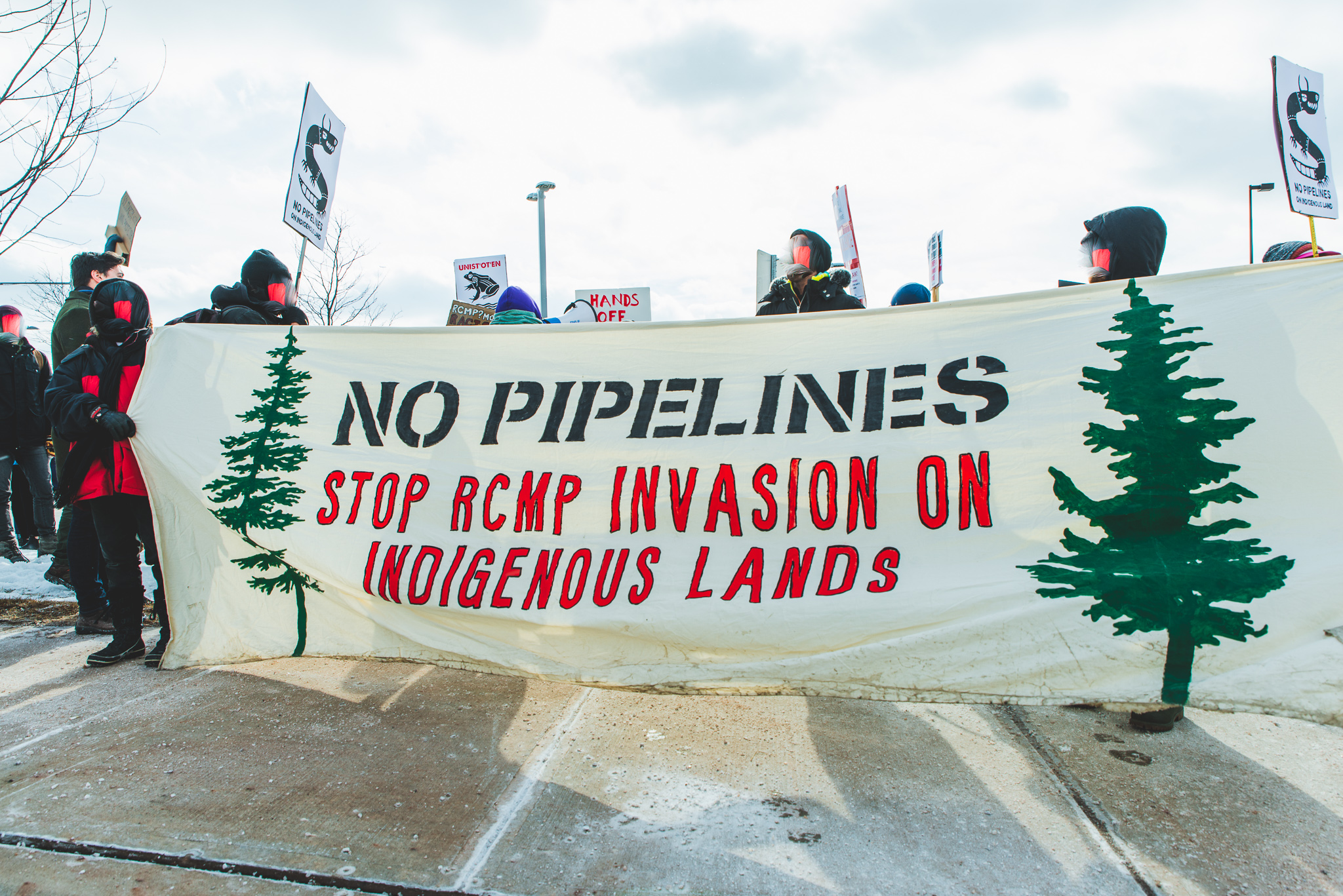 Protesters hold up a banner that says "No Pipelines: Stop RCMP Invasion on Indigenous Lands"