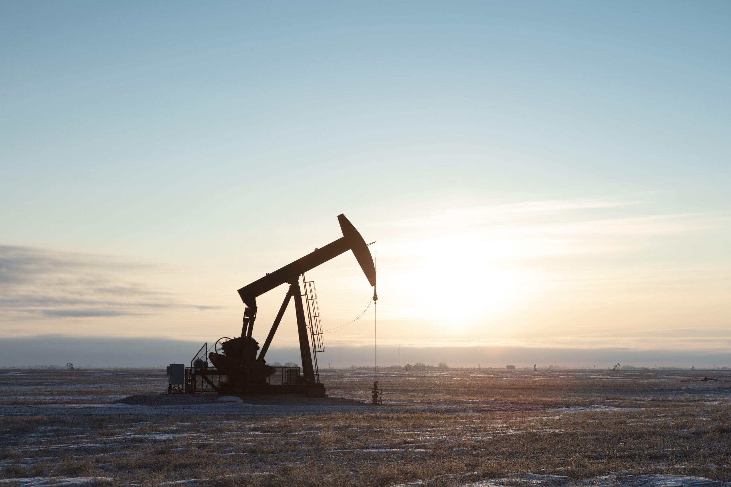 Single pump jack producing oil, sun rising. Image taken from a tripod.