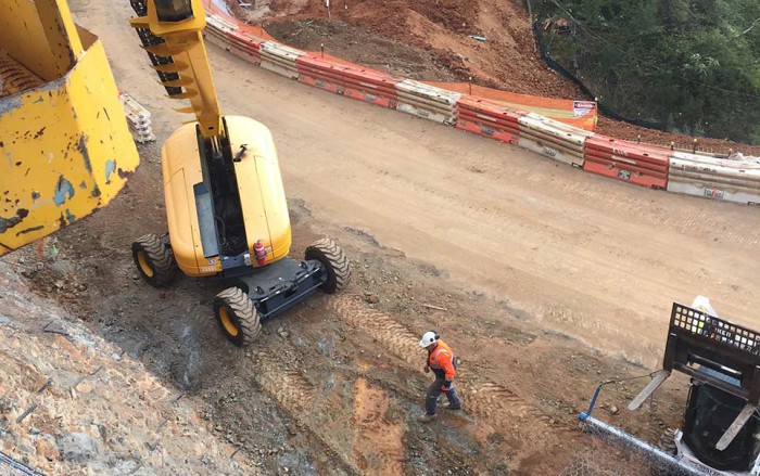 construction worker are mining site, walking near an excavator