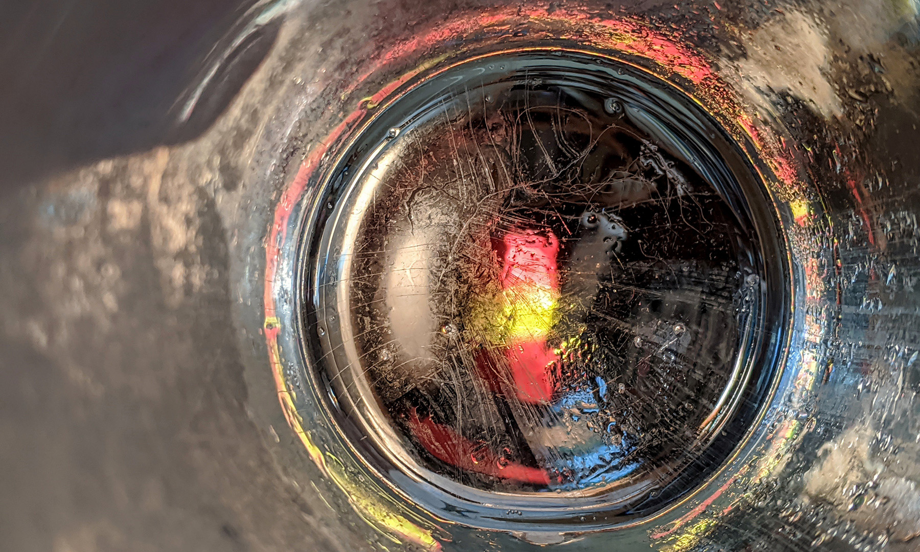 round piece of glass crack with yellow and pink lights going through it