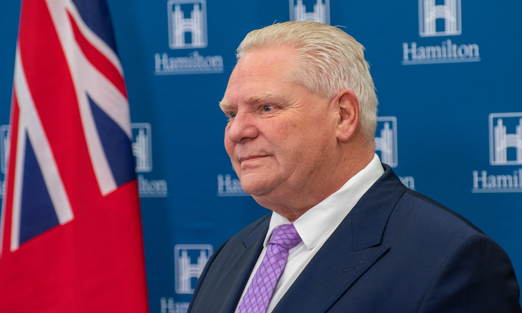 Ontario Premier Doug Ford with Ontario flag behind him.