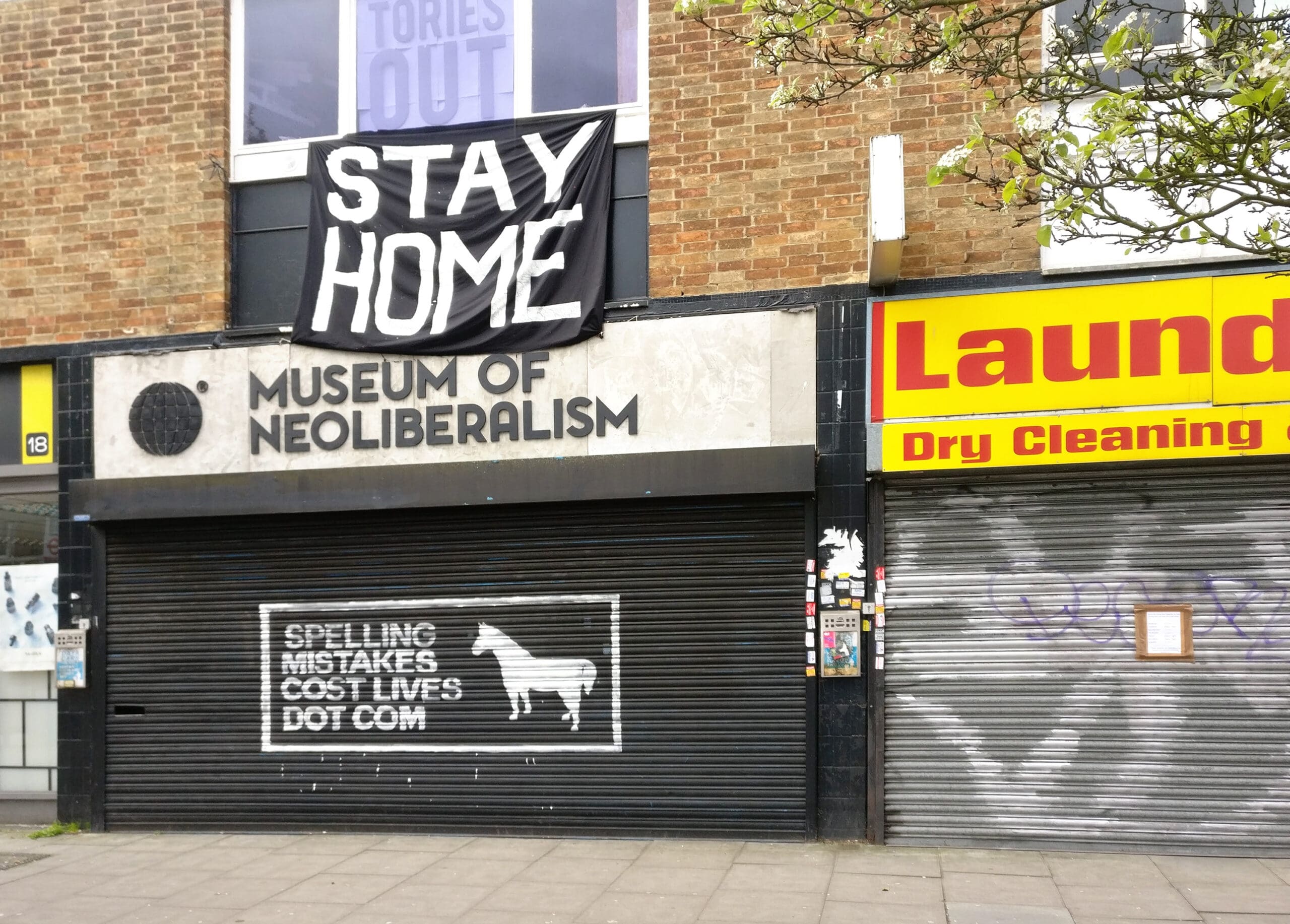 Large STAY HOME sign above closed Museum of Neoliberalism in Lewsiham. Shops and museums are closed during coronavirus covid-19 outbreak