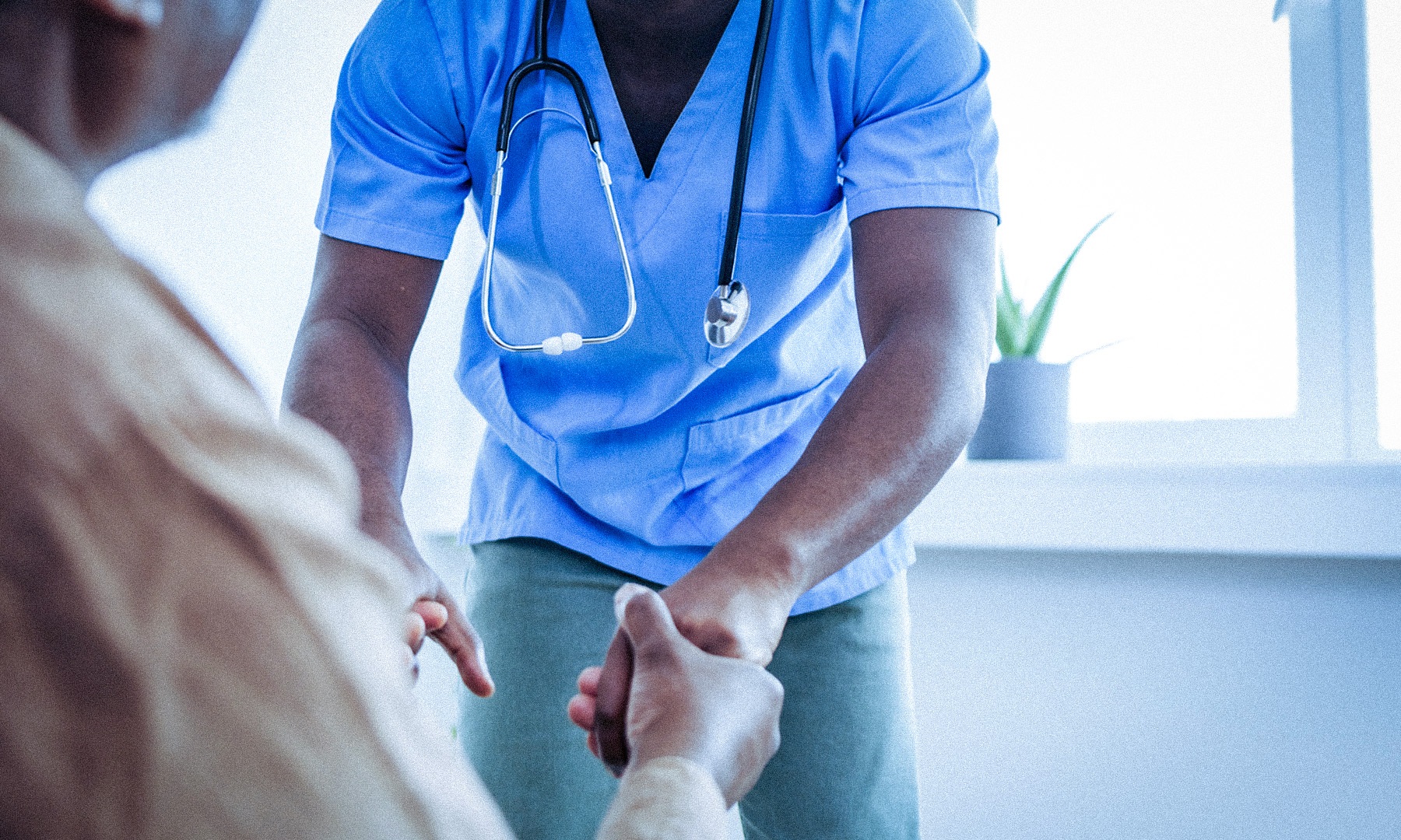 Hospital worker, face not shown, bending towards a patient