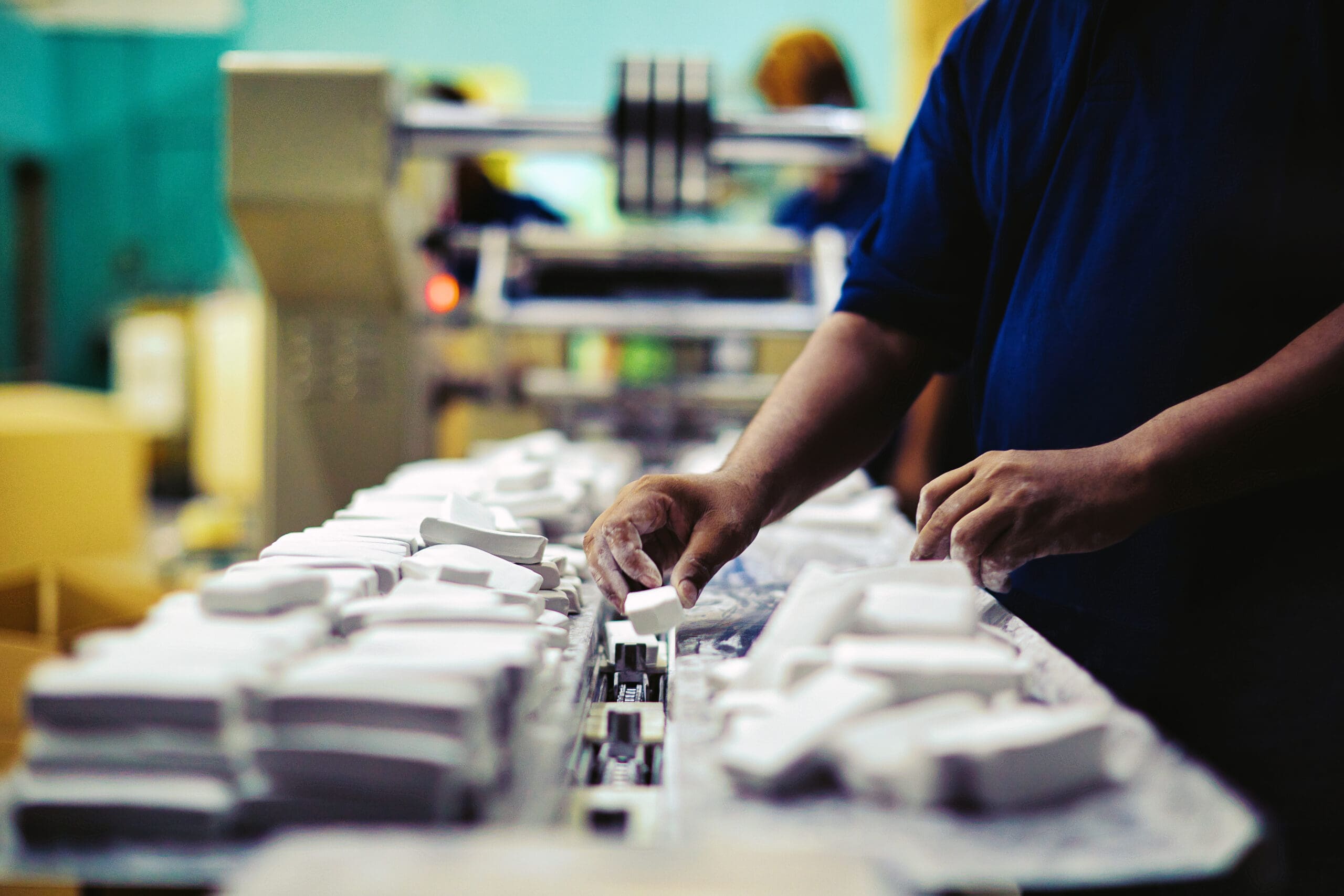 Team of factory workers quality inspecting the raw-material on production line. Image of one worker's hands moving products on the line