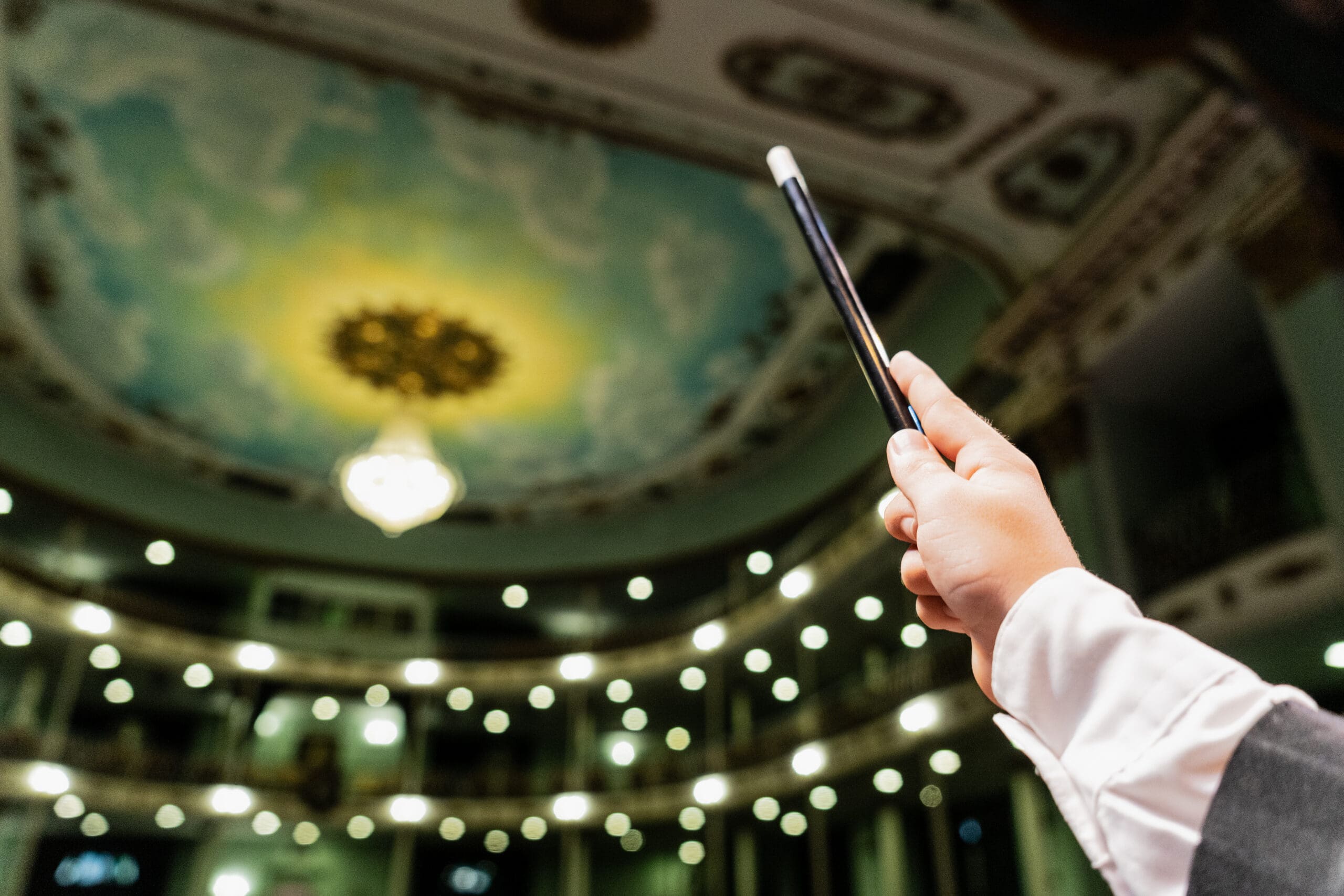 Close-up of a child magician boy holding a magic wand at stage theater